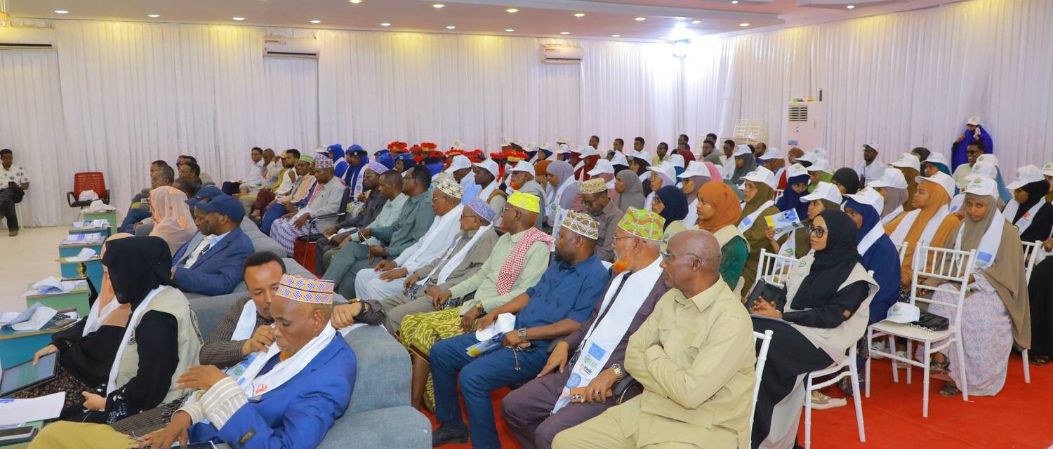 Elders, women leaders, youth and police officers seated together at a community event