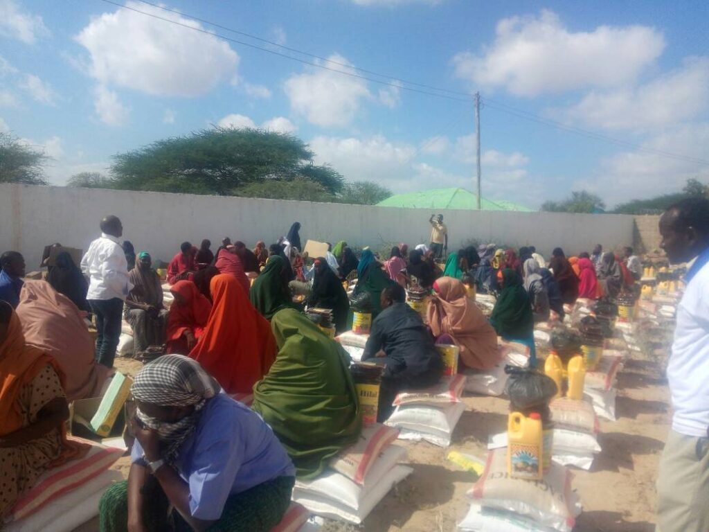 Families seated beside food kits during a SEMDO food distribution