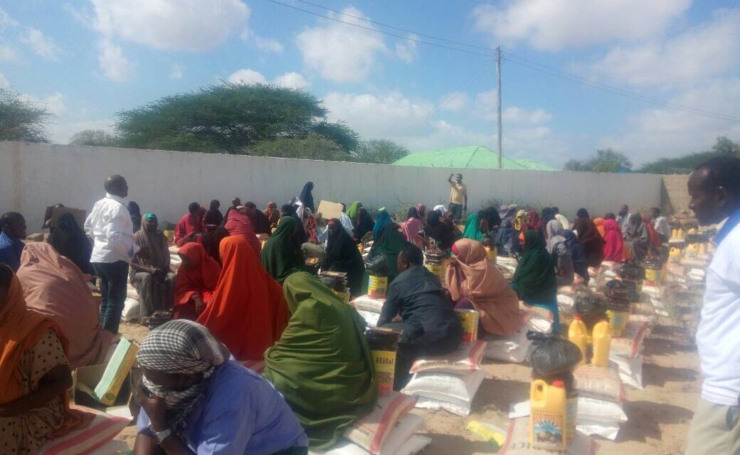 Families seated beside food kits during a SEMDO food distribution